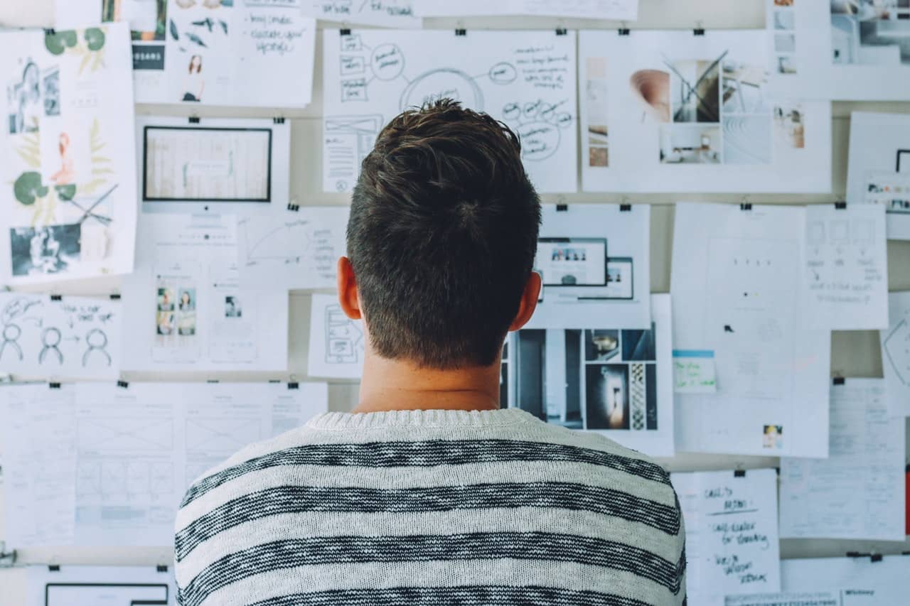 a man looking at papers on the wall
